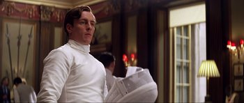 Movie still from “Die Another Day” (2002), directed by Lee Tamahori – A man in a white shirt holding a newspaper; Medium shot, Low angle