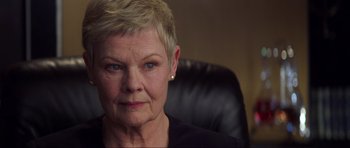Movie still from “Die Another Day” (2002), directed by Lee Tamahori – An older woman sitting in a leather chair; Close Up shot, Low angle