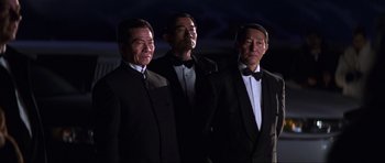 Movie still from “Die Another Day” (2002), directed by Lee Tamahori – A group of three men in tuxedos standing next to each other; Medium shot, Low angle
