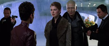 Movie still from “Die Another Day” (2002), directed by Lee Tamahori – A man and a woman standing next to each other in front of another man; Medium shot, Over the shoulder angle