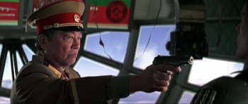 Movie still from “Die Another Day” (2002), directed by Lee Tamahori – A man holding a gun while standing in front of a window; Close Up shot, Low angle