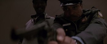 Movie still from “Die Hard 2” (1990), directed by Renny Harlin – Two men in uniform are holding guns in a room; Close Up shot, Low angle