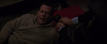 Movie still from “Die Hard 2” (1990), directed by Renny Harlin – A man in a sweater is holding a gun; Close Up shot, High angle