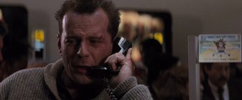 Movie still from “Die Hard 2” (1990), directed by Renny Harlin – A person talking on a cell phone; Close Up shot, Low angle