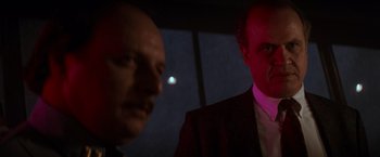 Movie still from “Die Hard 2” (1990), directed by Renny Harlin – Two men in suits and ties looking at each other in the dark; Close Up shot, Low angle
