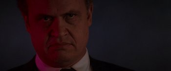 Movie still from “Die Hard 2” (1990), directed by Renny Harlin – A person wearing a suit and tie; Close Up shot, Low angle