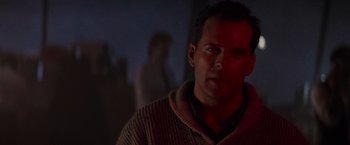 Movie still from “Die Hard 2” (1990), directed by Renny Harlin – A man in a sweater is looking at the camera; Close Up shot, Over the shoulder angle