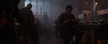 Movie still from “Die Hard 2” (1990), directed by Renny Harlin – A man sitting at a table reading a book; Medium shot, Low angle