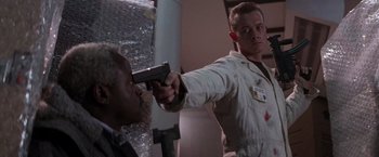 Movie still from “Die Hard 2” (1990), directed by Renny Harlin – A man holding a gun up to his face; Close Up shot, Low angle