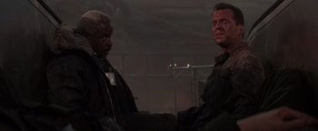 Movie still from “Die Hard 2” (1990), directed by Renny Harlin – Two men shake hands in a building; Medium shot, Low angle