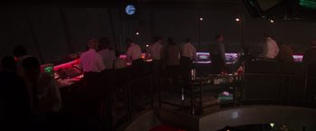 Movie still from “Die Hard 2” (1990), directed by Renny Harlin – A group of people standing around a bar at night; Extreme Wide shot, High angle