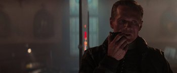 Movie still from “Die Hard 2” (1990), directed by Renny Harlin – A man in a brown jacket standing in front of a window; Close Up shot, Over the shoulder angle