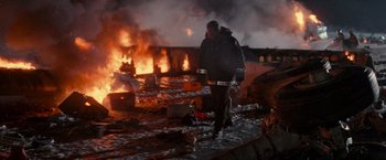 Movie still from “Die Hard 2” (1990), directed by Renny Harlin – A man walking in front of a burning building at night; Wide shot, Low angle
