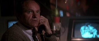 Movie still from “Die Hard 2” (1990), directed by Renny Harlin – A man talking on a phone while wearing a suit and tie; Close Up shot, Low angle