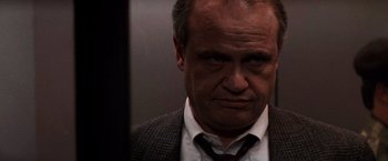 Movie still from “Die Hard 2” (1990), directed by Renny Harlin – A person wearing a suit and tie; Close Up shot, Low angle