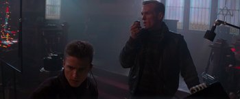Movie still from “Die Hard 2” (1990), directed by Renny Harlin – A man is talking on a cell phone while another man watches; Medium shot, Low angle