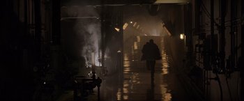 Movie still from “Die Hard 2” (1990), directed by Renny Harlin – A man walking down a wet walkway in the dark; Wide shot, Low angle