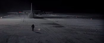 Movie still from “Die Hard 2” (1990), directed by Renny Harlin – A man standing in the middle of an airport runway at night; Extreme Wide shot, High angle
