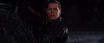 Movie still from “Die Hard 2” (1990), directed by Renny Harlin – A person wearing a leather jacket holding a gun; Close Up shot, Low angle