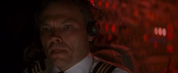 Movie still from “Die Hard 2” (1990), directed by Renny Harlin – A man wearing a headset in front of a red background; Close Up shot, Overhead angle