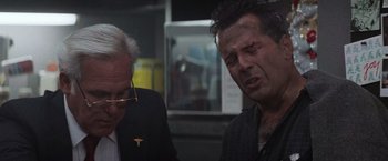 Movie still from “Die Hard 2” (1990), directed by Renny Harlin – Two men sitting next to each other in a room; Close Up shot, Over the shoulder angle