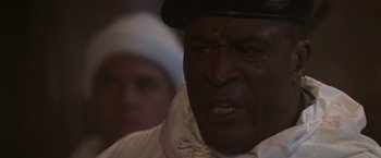 Movie still from “Die Hard 2” (1990), directed by Renny Harlin – An older man wearing a black hat and a white shirt; Close Up shot, Low angle