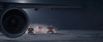 Movie still from “Die Hard 2” (1990), directed by Renny Harlin – A group of firetrucks driving down a snow covered road; Extreme Wide shot, Low angle