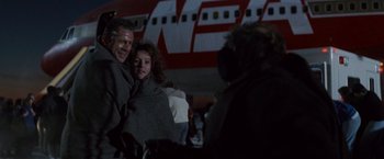 Movie still from “Die Hard 2” (1990), directed by Renny Harlin – A man and a woman standing in front of an airplane; Medium shot, Low angle