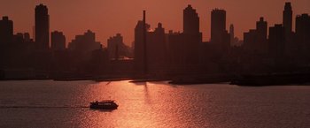 Movie still from “Die Hard with a Vengeance” (1995), directed by John McTiernan – A boat on a body of water near a large city; Extreme Wide shot, High angle