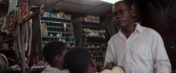 Movie still from “Die Hard with a Vengeance” (1995), directed by John McTiernan – A group of people sitting in a room; Medium shot, Low angle
