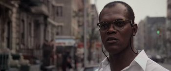 Movie still from “Die Hard with a Vengeance” (1995), directed by John McTiernan – A person wearing glasses on a city street; Close Up shot, Low angle