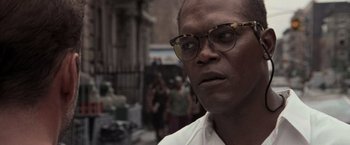 Movie still from “Die Hard with a Vengeance” (1995), directed by John McTiernan – A person wearing glasses on a city street; Close Up shot, Low angle
