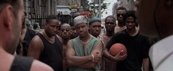 Movie still from “Die Hard with a Vengeance” (1995), directed by John McTiernan – A group of men standing next to each other on a street; Medium shot, Low angle
