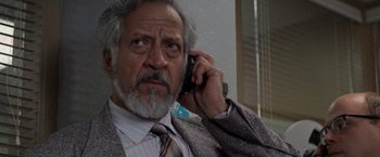 Movie still from “Die Hard with a Vengeance” (1995), directed by John McTiernan – An older man talking on a cell phone while wearing a suit; Close Up shot, Low angle