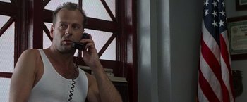 Movie still from “Die Hard with a Vengeance” (1995), directed by John McTiernan – A man talking on a phone while sitting in a room; Close Up shot, Low angle