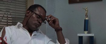 Movie still from “Die Hard with a Vengeance” (1995), directed by John McTiernan – A man in a white dress shirt is holding a pair of eyeglasses; Close Up shot, Low angle