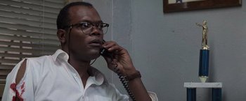 Movie still from “Die Hard with a Vengeance” (1995), directed by John McTiernan – A man talking on a phone while wearing glasses; Close Up shot, Low angle