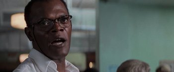 Movie still from “Die Hard with a Vengeance” (1995), directed by John McTiernan – A person wearing a white shirt and glasses; Close Up shot, Over the shoulder angle