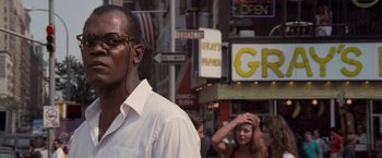 Movie still from “Die Hard with a Vengeance” (1995), directed by John McTiernan – A man in a white dress shirt is walking down the street; Close Up shot, Low angle
