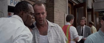 Movie still from “Die Hard with a Vengeance” (1995), directed by John McTiernan – A man in a plaid shirt is standing next to another man in an orange vest; Close Up shot, Low angle