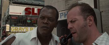 Movie still from “Die Hard with a Vengeance” (1995), directed by John McTiernan – Two men standing next to each other on the street; Close Up shot, Low angle