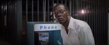 Movie still from “Die Hard with a Vengeance” (1995), directed by John McTiernan – A man in a white dress shirt is leaning against a phone booth; Close Up shot, Low angle