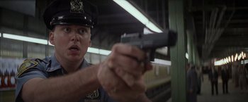 Movie still from “Die Hard with a Vengeance” (1995), directed by John McTiernan – A police officer holding a gun in a train station; Close Up shot, Low angle