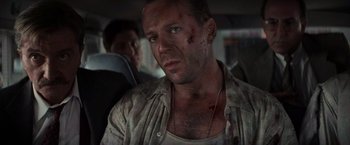 Movie still from “Die Hard with a Vengeance” (1995), directed by John McTiernan – A person in a car on a street; Close Up shot, Over the shoulder angle
