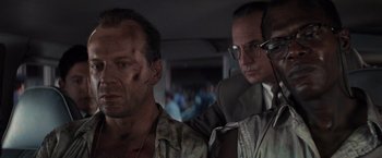 Movie still from “Die Hard with a Vengeance” (1995), directed by John McTiernan – Two men in a car , one of which has a broken arm on his head; Close Up shot, Over the shoulder angle