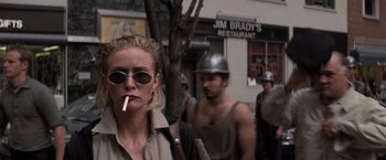 Movie still from “Die Hard with a Vengeance” (1995), directed by John McTiernan – A woman smoking a cigarette while standing next to a man; Close Up shot, Low angle