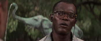 Movie still from “Die Hard with a Vengeance” (1995), directed by John McTiernan – A person wearing glasses with an elephant in the background; Close Up shot, Low angle