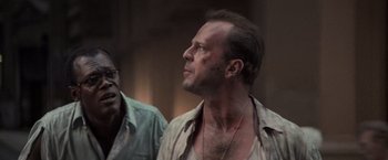 Movie still from “Die Hard with a Vengeance” (1995), directed by John McTiernan – A man with a shaved head and a beard is standing next to another man with a beard; Close Up shot, Low angle