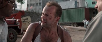 Movie still from “Die Hard with a Vengeance” (1995), directed by John McTiernan – A person wearing a shirt and a necklace; Close Up shot, Over the shoulder angle