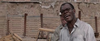 Movie still from “Die Hard with a Vengeance” (1995), directed by John McTiernan – A man with glasses is laughing while another man is sitting on a chair; Close Up shot, Low angle